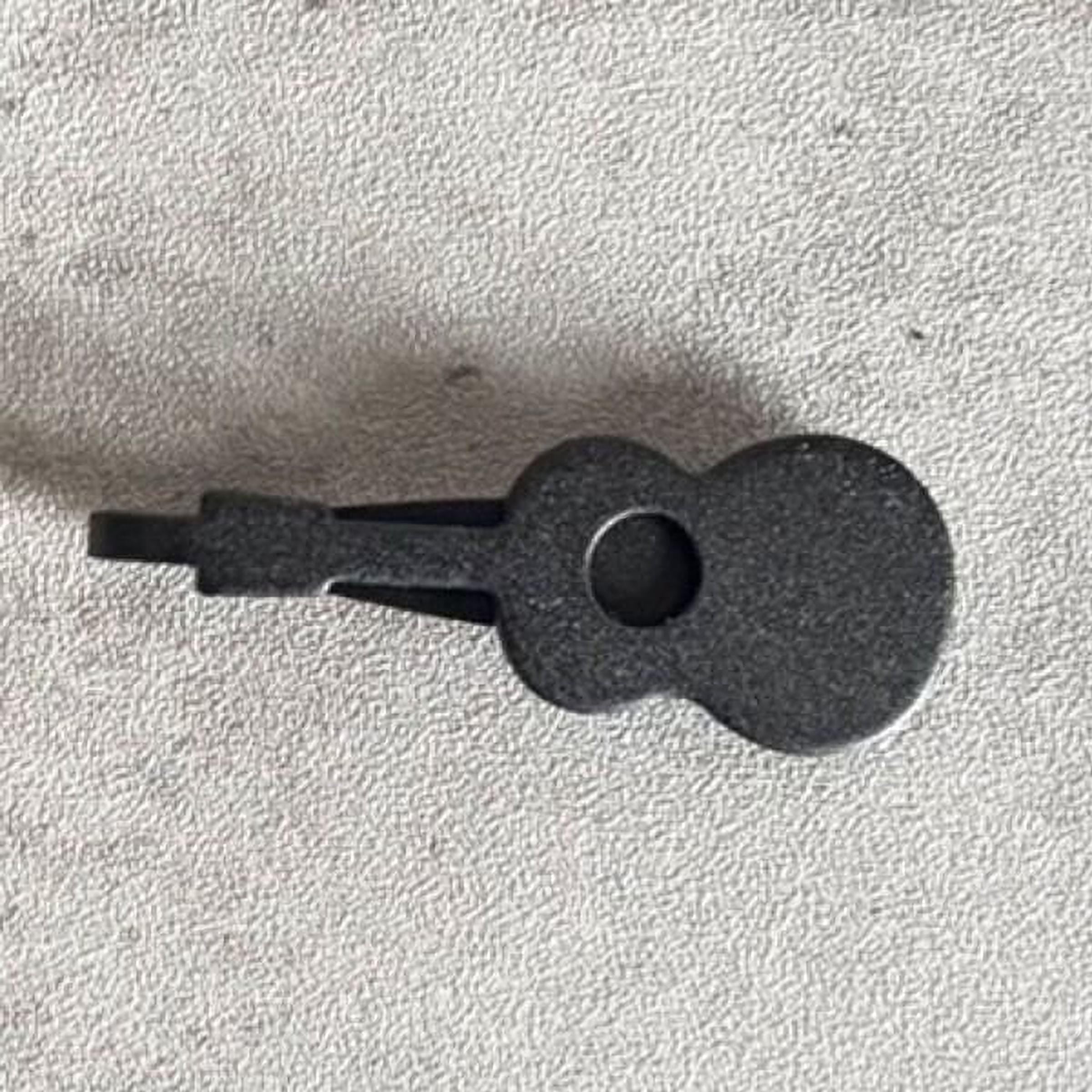 A black guitar-shaped object is shown on a textured surface.