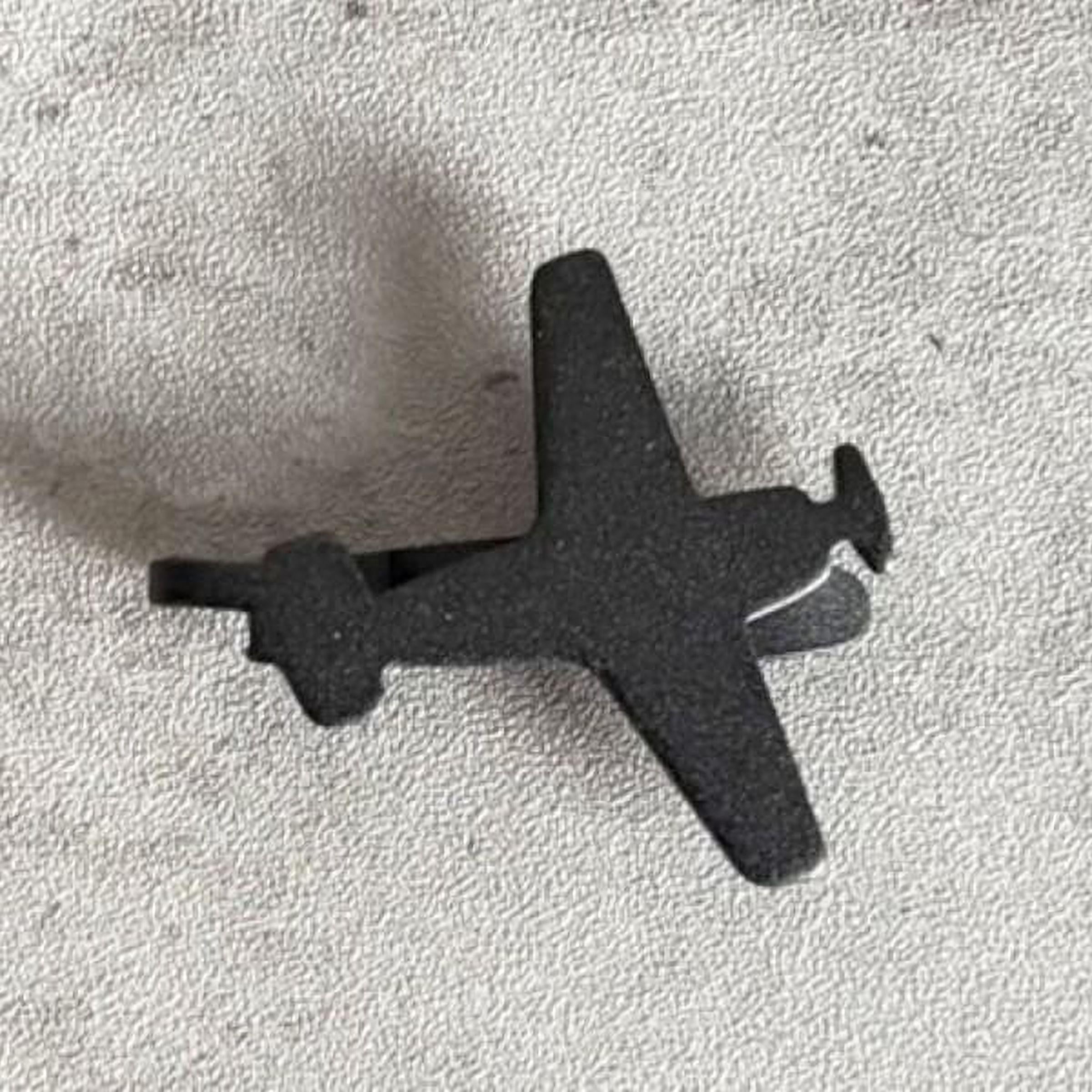 A black metal airplane propeller is shown against a textured gray background.