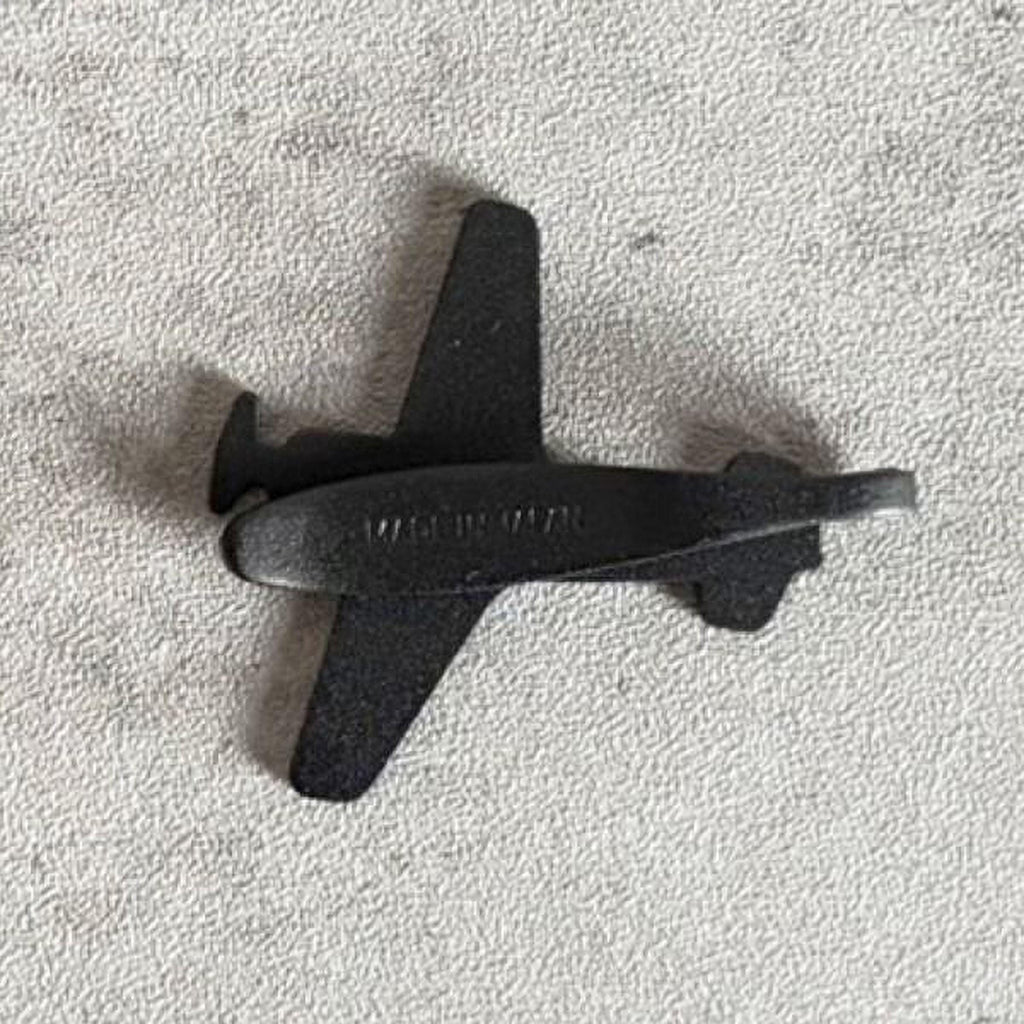 A small black airplane figurine is shown on a textured gray surface.