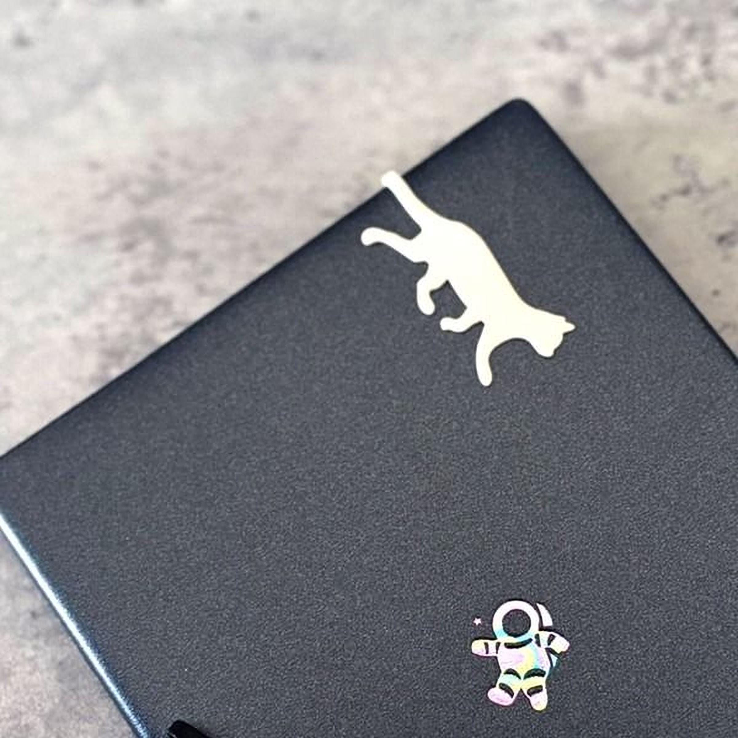 a black laptop with a cat sticker and a small astronaut sticker on its surface.