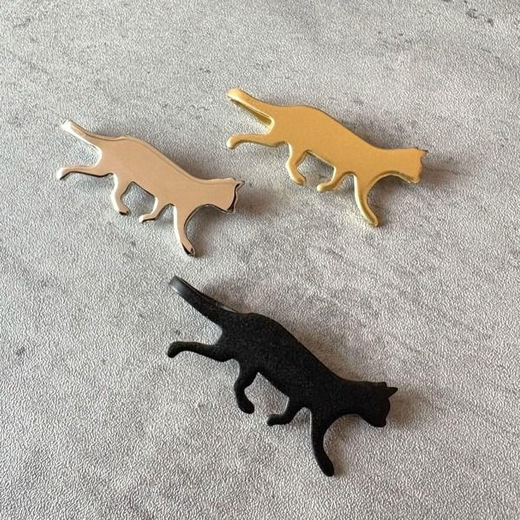 three cat-shaped objects, each in a different color: gold, black, and brown.