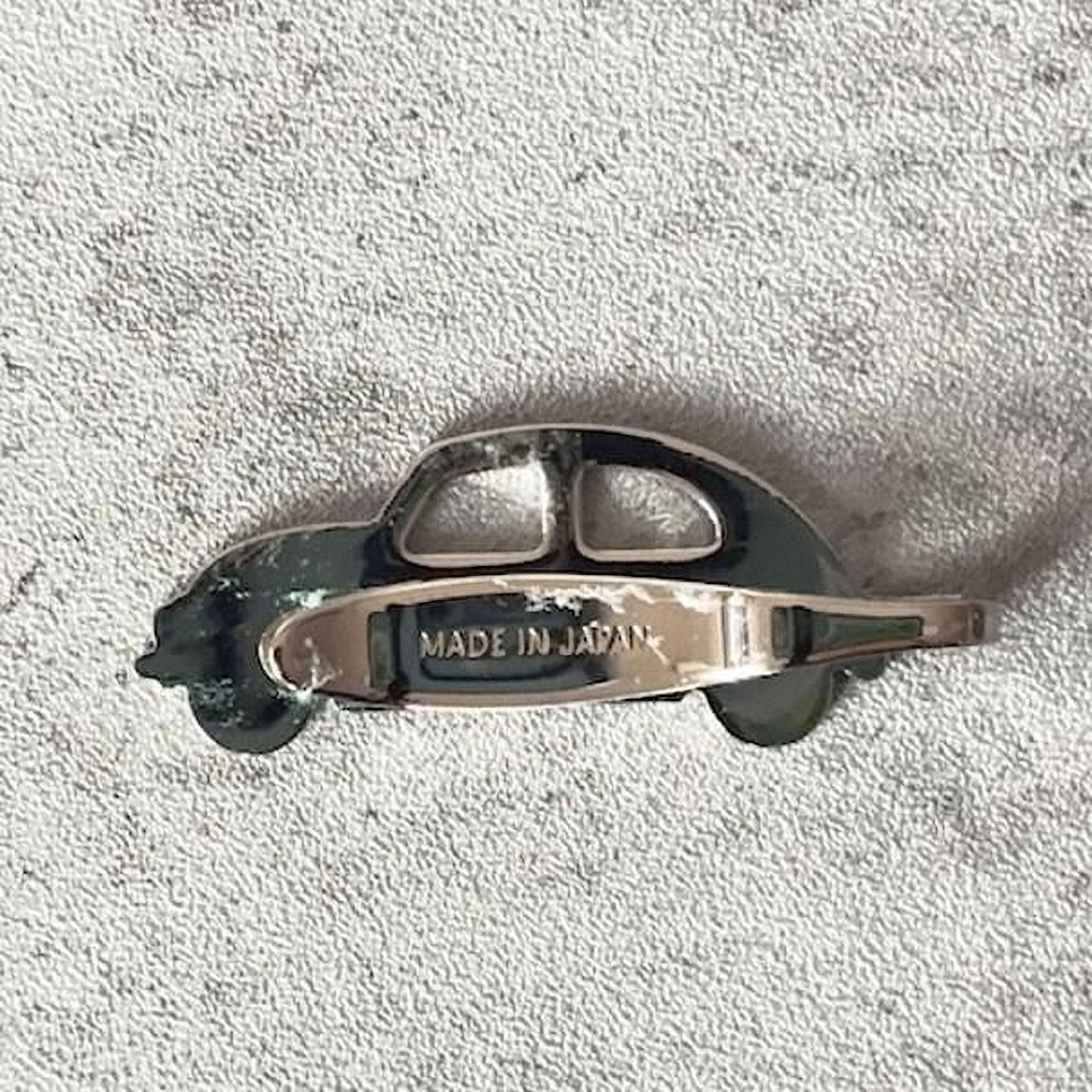 A silver-colored metal object resembling a car or vehicle, with the text "MADE IN JAPAN" printed on it.