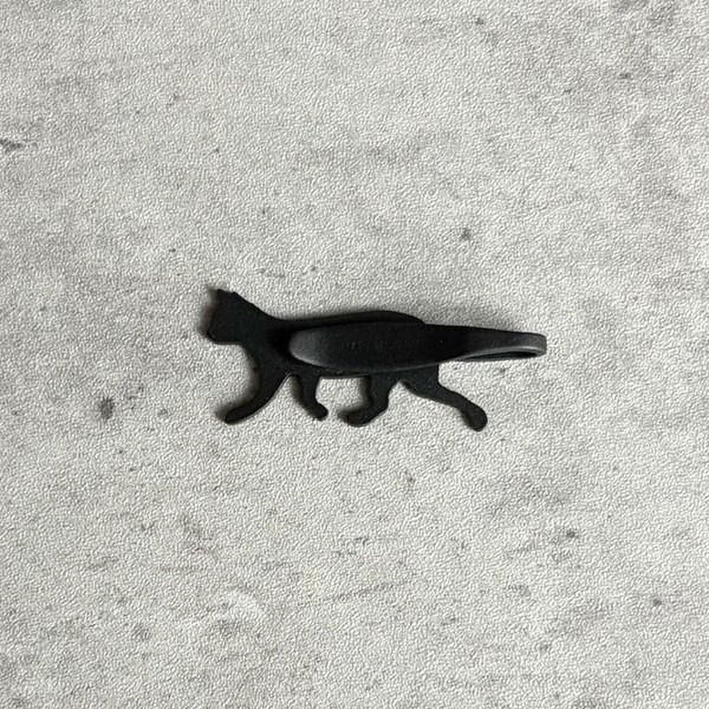A black cat-shaped object is shown against a textured gray background.