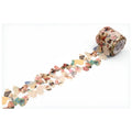 A roll of decorative paper tape with various colorful patterns and images printed on it, lying on a white surface.