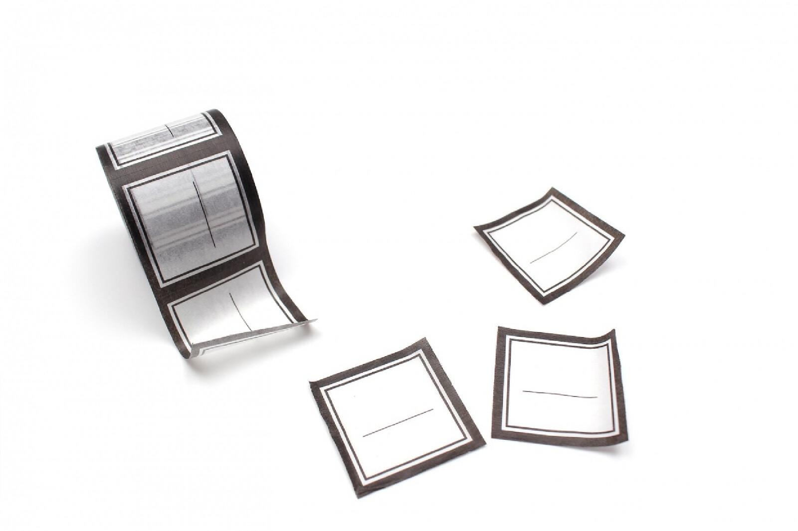 a roll of paper with a black and white design, along with three additional paper pieces with similar black and white designs.