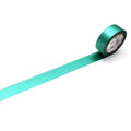 A roll of green metallic tape is lying on a white surface, with a white clock face visible on the tape.