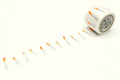 A roll of white and orange tape with a pattern of small orange candles drawn on it, arranged in a row on a white background.