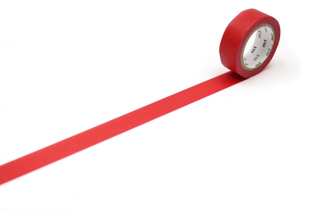 A roll of red tape with a clock face on it is placed on a white surface, with a long red strip extending from the tape.
