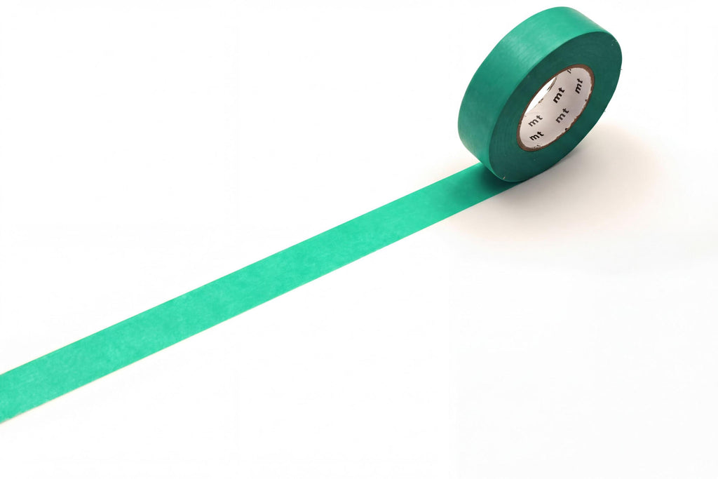 A roll of green masking tape is lying on a white surface, with a green strip extending from the tape.