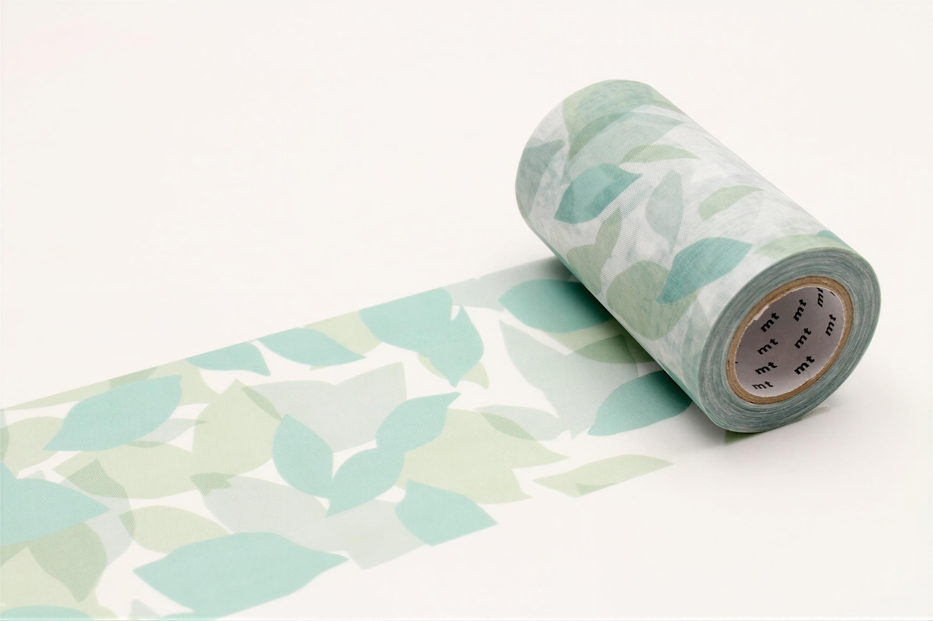 A roll of green and white patterned tape is lying on a white surface, with a leaf-like pattern visible on the tape.