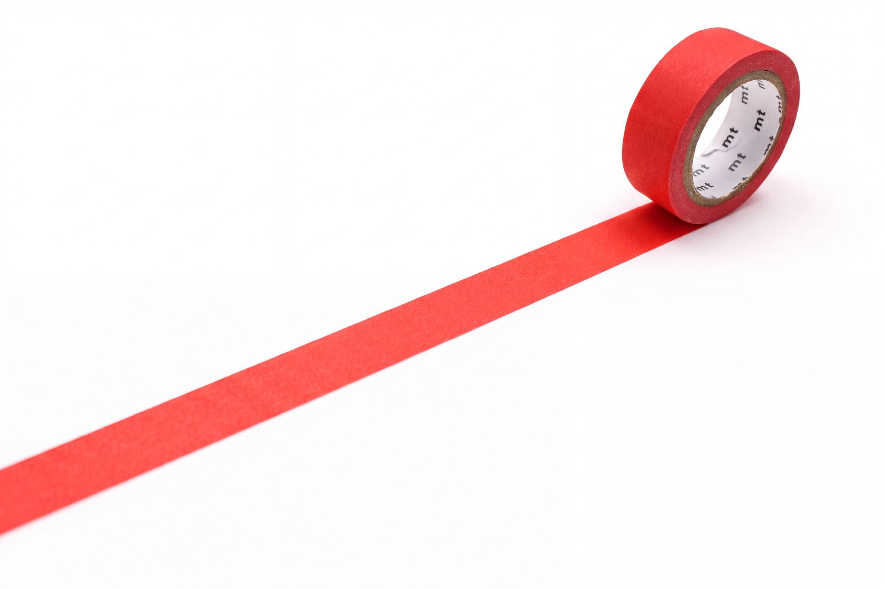 A roll of red masking tape is placed on a white surface, with a long red strip extending from the tape.
