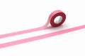 A roll of pink masking tape is lying on its side on a white background.