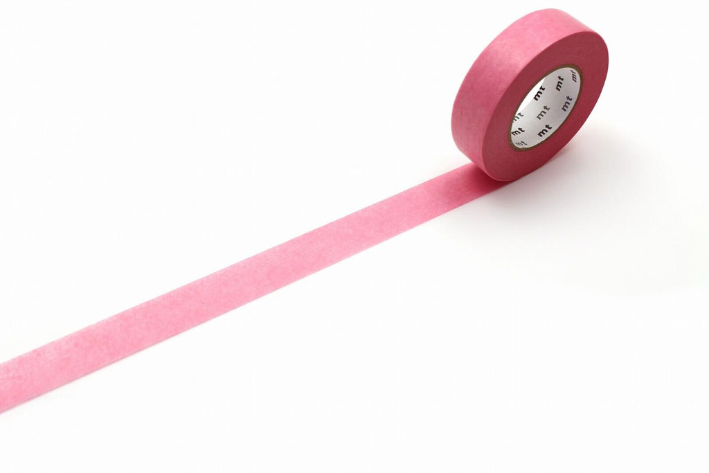 A roll of pink masking tape is lying on a white surface, with a pink line running across it.