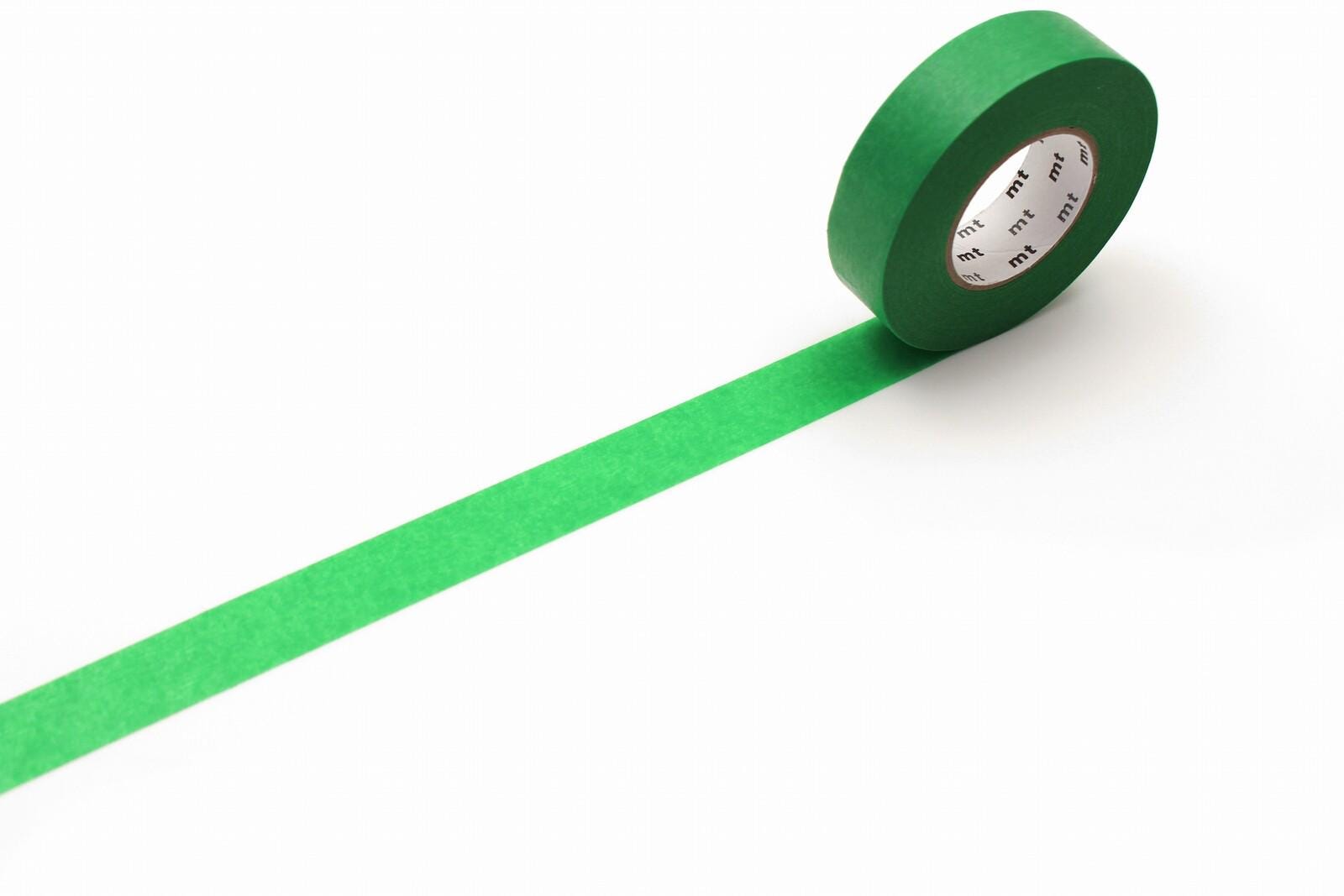 A roll of green masking tape with a white label is placed on a white surface, with a green line extending from the tape.