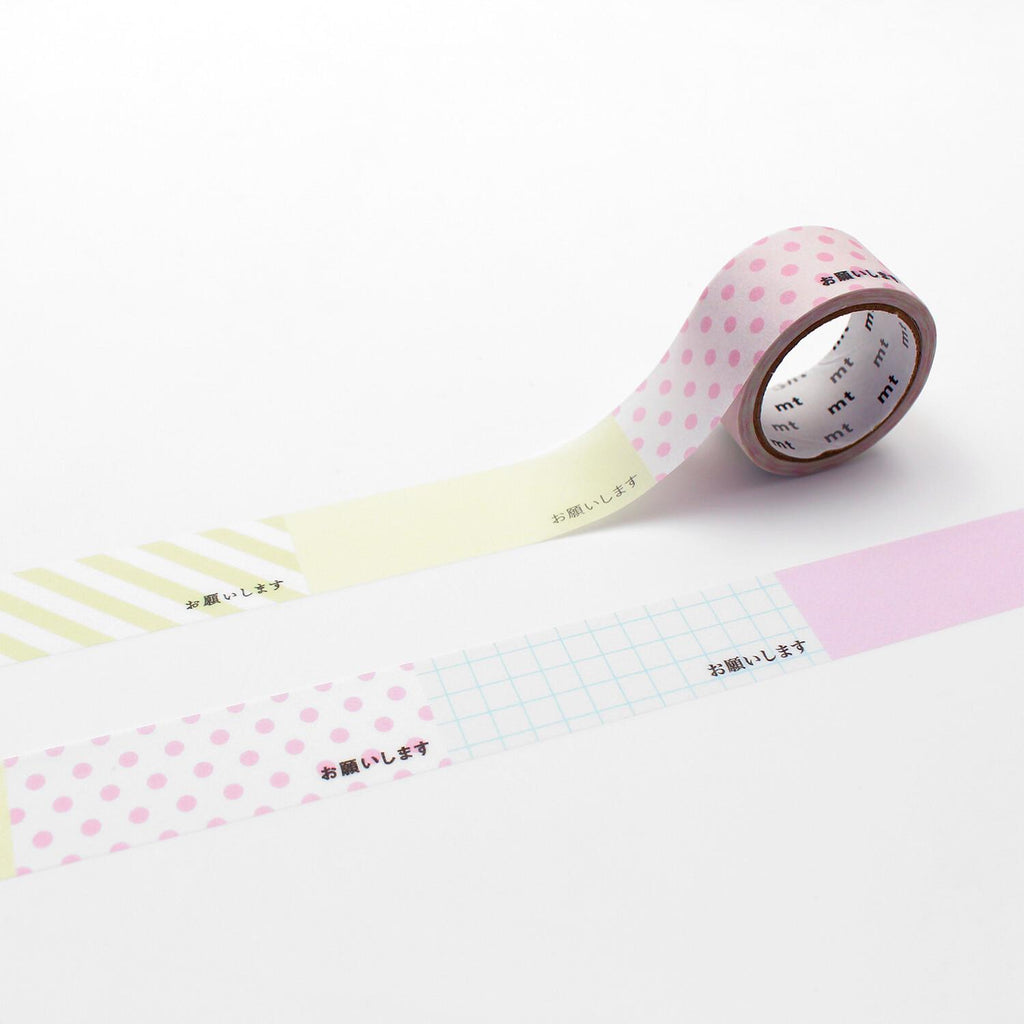 a roll of pink and white polka dot tape with Japanese text on it, placed on a white surface.