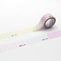 a roll of pink and white polka dot tape with Japanese text on it, placed on a white surface.