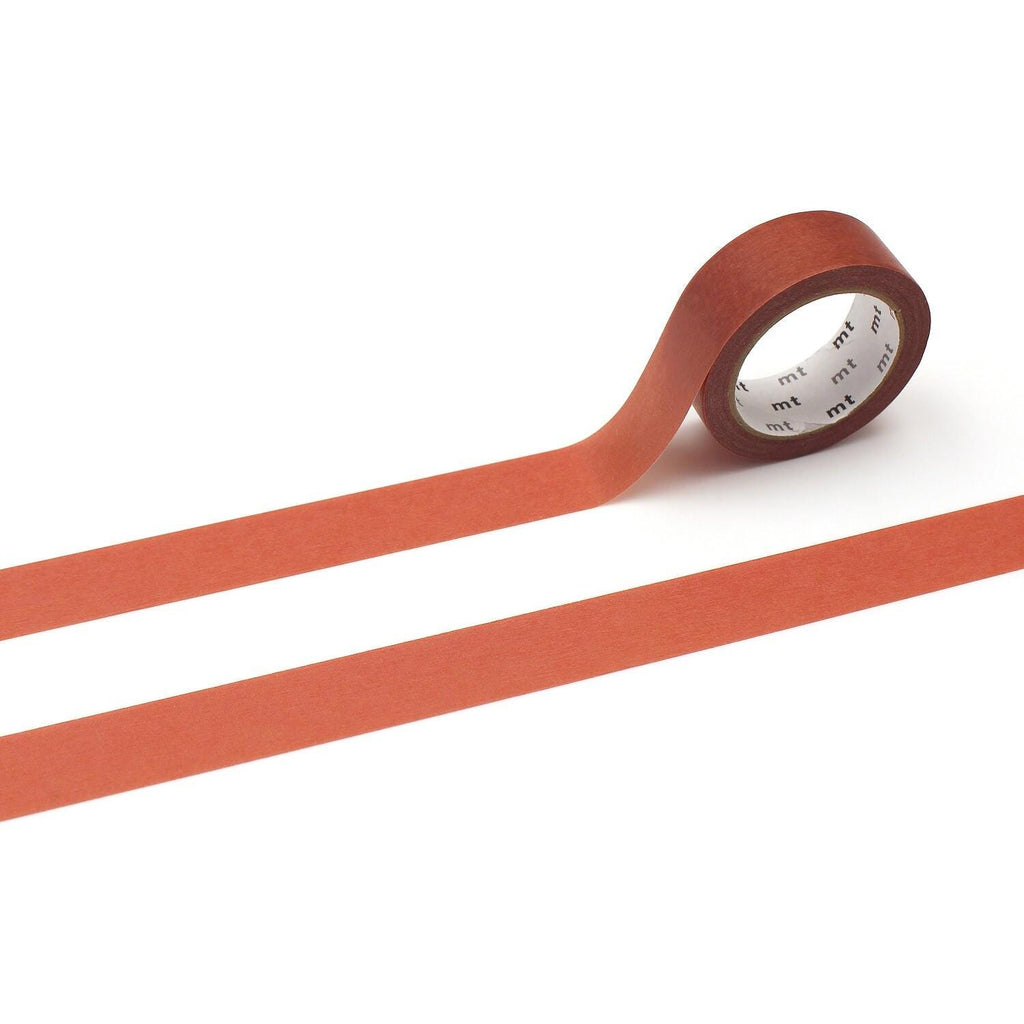 a roll of red tape with a white label, lying on a white surface.