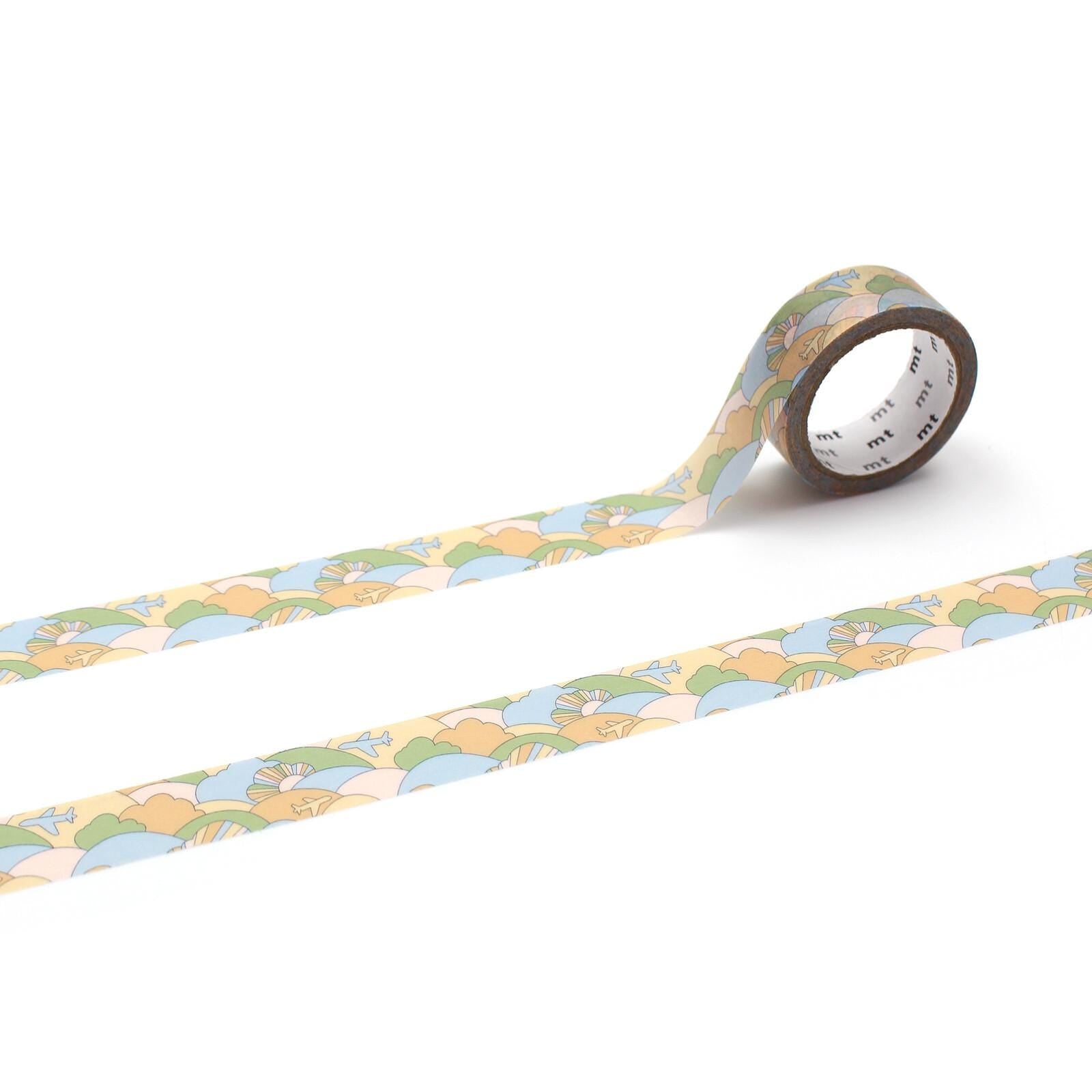 a roll of patterned tape with a repeating design of green, blue, and orange colors. The tape is lying on a white surface, with one end facing upwards and the other end facing downwards.