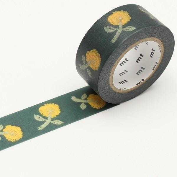A roll of black and green floral patterned tape with yellow flowers on it, lying on a white surface.