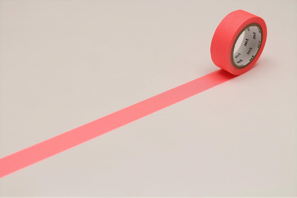 A roll of red tape with a white center is placed on a white surface, with a long pink line extending from the tape.