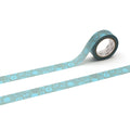 a roll of blue and green patterned tape with a repeating design of circles and lines, lying on a white background.